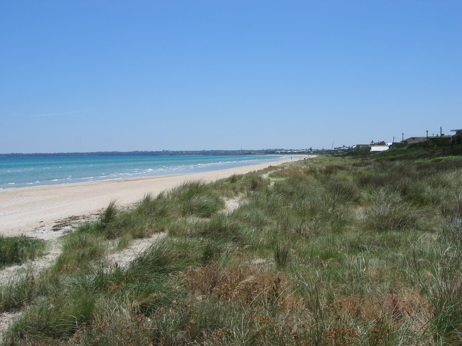 The sandy Aspendale foreshore and turquoise Port Phillip water where Mordialloc Sailing Club launches off the beach