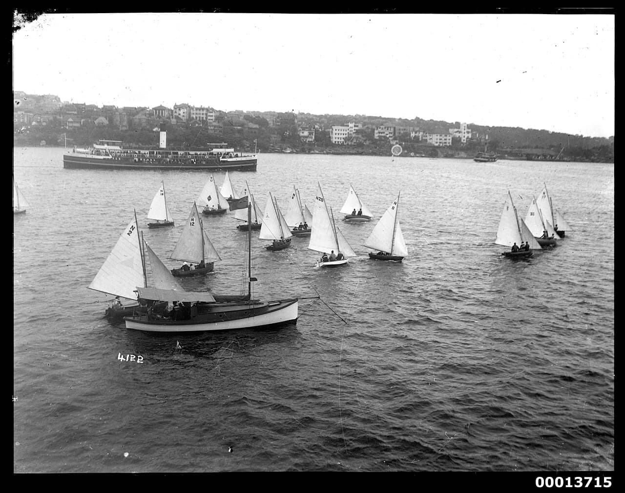 Racing skiffs pass a sailing boat on Sydney Harbour