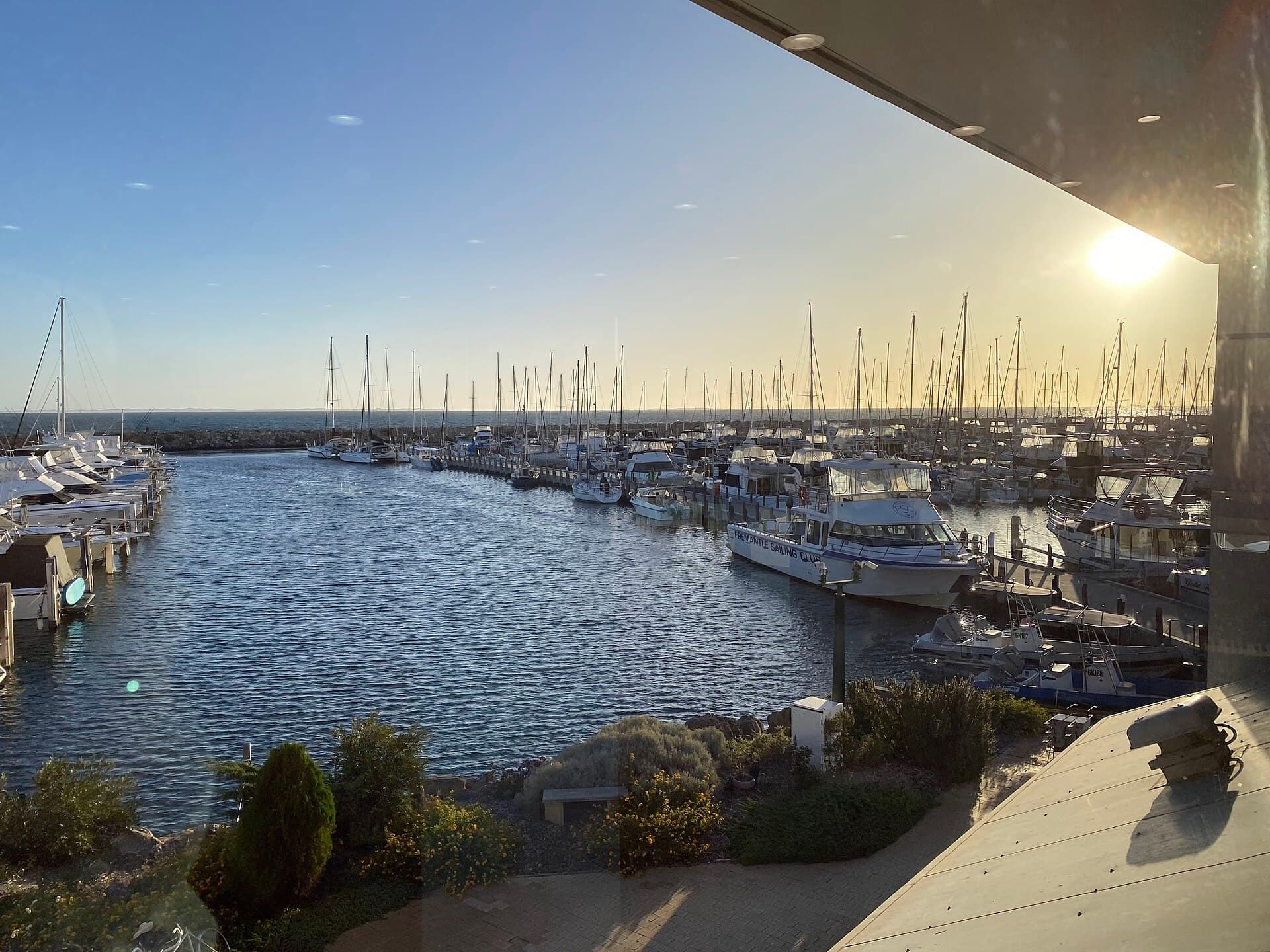 The harbour entrance at the Fremantle Sailing Club, with a Fremantle Sailing Club vessel and moored boats and the Indian Ocean beyond